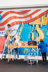 ACECO employees helping Mike Miller and Greg Didyoung install the mural